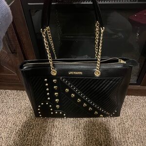 Love Moschino black handbag with gold heart studs and red interior.